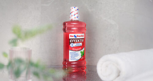 A bottle of One Drop Only Effektiv mouthwash sits on a countertop next to a rolled towel, promoting effective Mundhygiene.