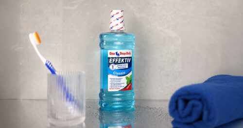A bottle of Effektiv mouthwash sits beside a toothbrush and a blue towel, emphasizing essential Mundhygiene routines.