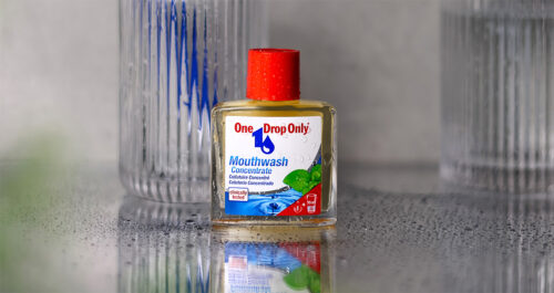 Eine One Drop Only Mundwasserflasche steht auf einer nassen Oberfläche, was die Bedeutung der Mundhygiene unterstreicht.