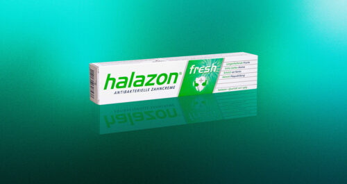 Eine Packung Halazon antibakterielle Zahnpasta liegt auf einem frischen, verlaufenden grünen Hintergrund.